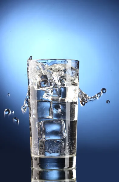 파란색 배경에 얼음 조각으로 유리에 신선한 물 — 스톡 사진