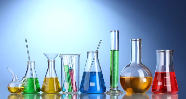 Different laboratory glassware with color liquid and with reflection on blu — Stock Photo, Image