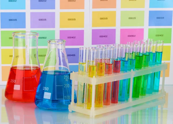 Test tüpleri ve renk örnekleri arka plan üzerinde renkli sıvı şişe — Stok fotoğraf