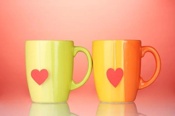Two cups and tea bags with red heart-shaped label on red background — Stock Photo, Image