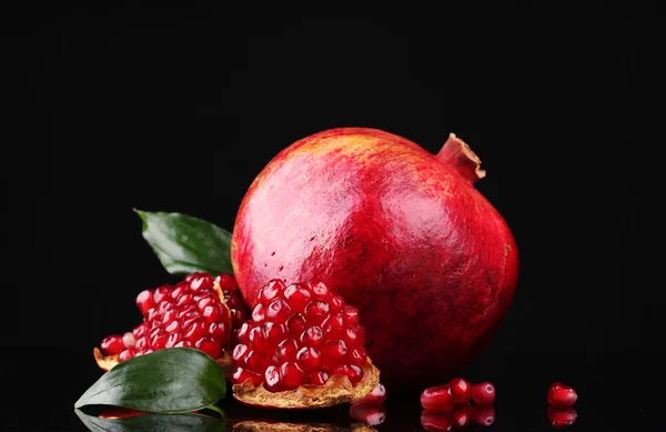Mogen granatäpple frukt med lämnar på svart bakgrund — Stockfoto