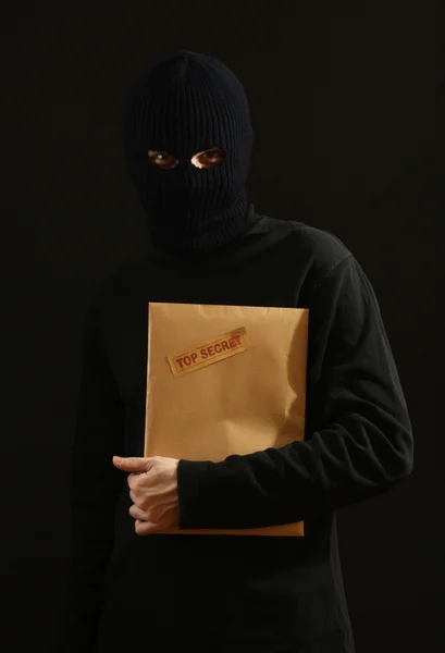 Bandido en máscara negra con sobre de alto secreto aislado en negro — Foto de Stock