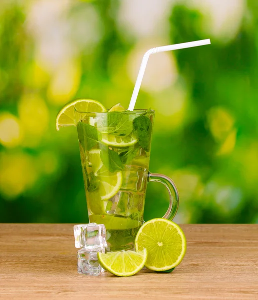 Bicchiere di cocktail con lime e menta su sfondo verde tavolo di legno — Foto Stock