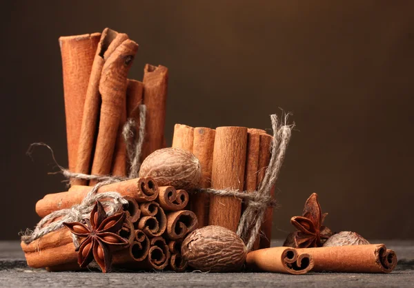 Cinnamon sticks, nutmeg and anise on wooden table on brown background — Stock Photo, Image