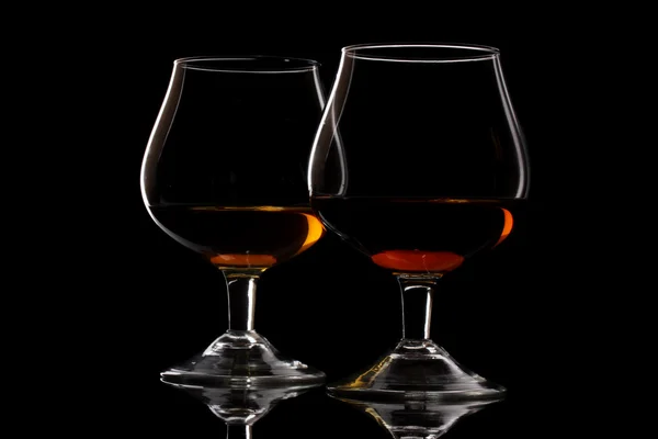 Dois copos de conhaque no fundo preto — Fotografia de Stock
