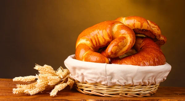 Pan horneado en cesta sobre mesa de madera sobre fondo marrón —  Fotos de Stock