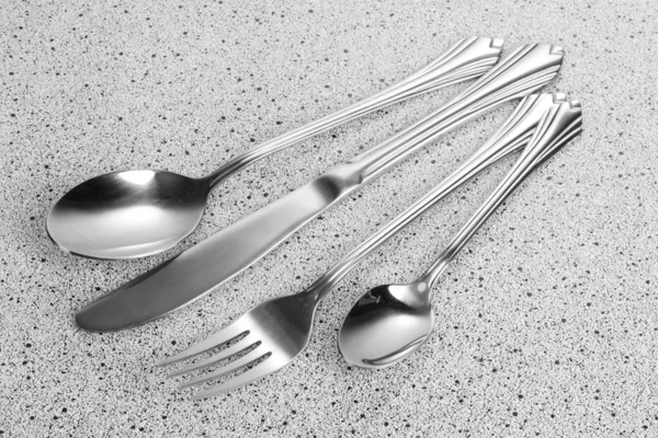 Πιρούνι, κουτάλι και μαχαίρι στο μαρμάρινο τραπέζι — Φωτογραφία Αρχείου