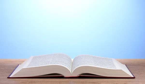 Buch aufschlagen auf Holztisch auf blauem Hintergrund — Stockfoto