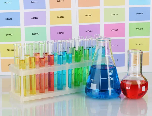 Tubos de ensayo y frascos con líquido de color sobre el fondo de muestras de color — Foto de Stock