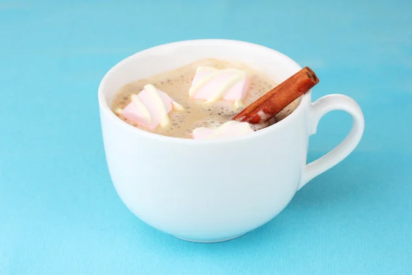 Xícara de cappucino com marshmallows e canela no fundo azul — Fotografia de Stock