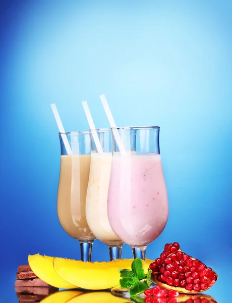 Meyve ve çikolata üzerinde mavi arka plan ile süt sallar — Stok fotoğraf
