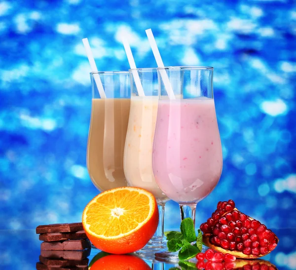 Meyve ve çikolata üzerinde mavi arka plan ile süt sallar — Stok fotoğraf