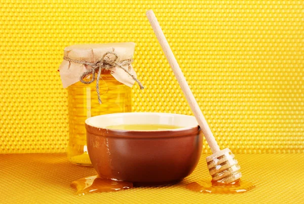 Tarro de miel, tazón y rociador de madera con miel en panal amarillo respaldo —  Fotos de Stock