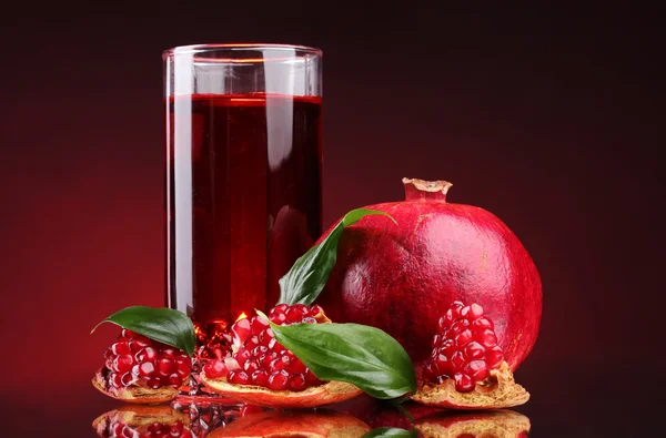 Masak pomergranate dan segelas jus di latar belakang merah — Stok Foto