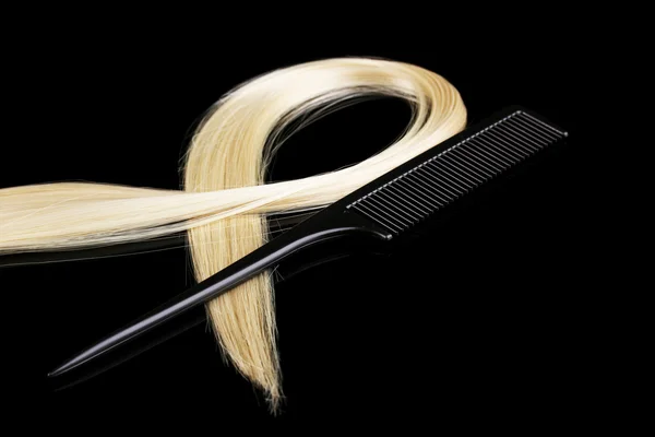 Shiny blond hair and comb isolated on black — Stock Photo, Image