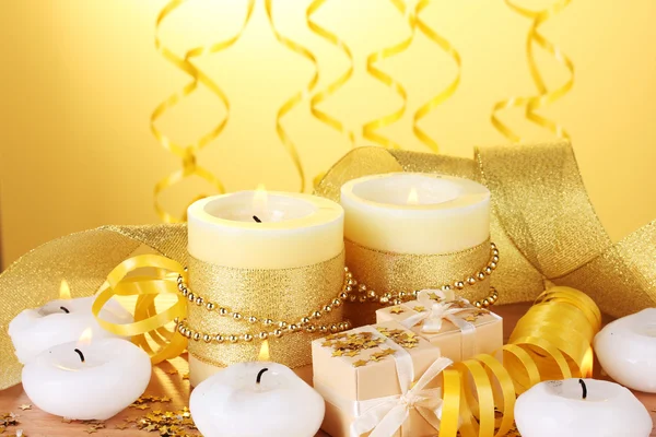 美丽的蜡烛，礼品和在黄色背景上的木桌上的装饰 — 图库照片