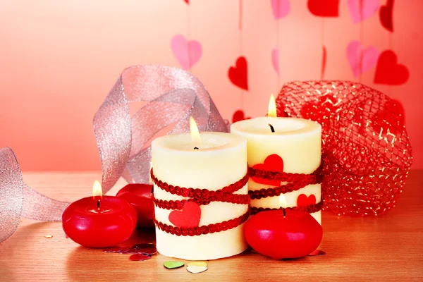 バレンタインの日赤の背景に木製のテーブルの上のキャンドル — ストック写真