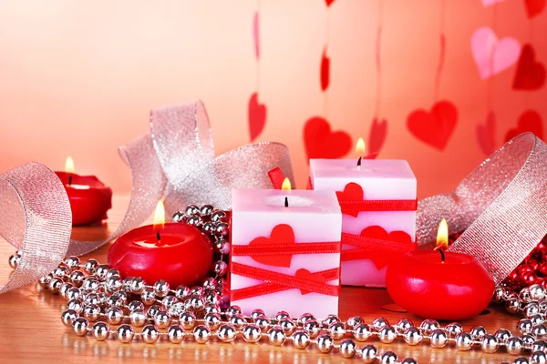 Kerzen zum Valentinstag auf Holztisch auf rotem Hintergrund — Stockfoto