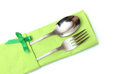 Fork and spoon in a green cloth with a bow isolated on white