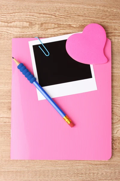 Fotografický papír a růžový notebook na dřevěné pozadí — Stock fotografie