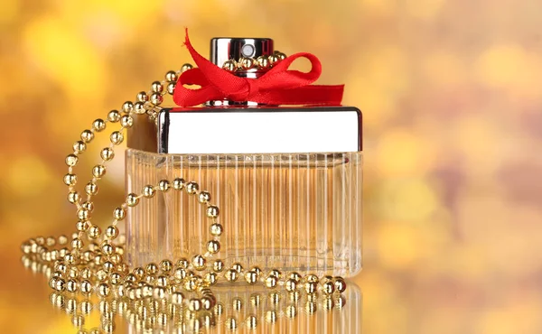 Flakon perfum z czerwoną kokardą na żółtym tle — Zdjęcie stockowe