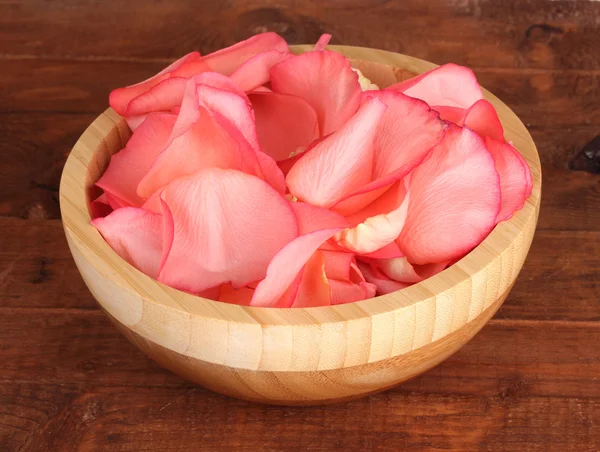 Belas pétalas de rosa rosa em tigela de madeira na mesa — Fotografia de Stock