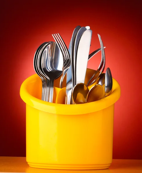 Mutfak bıçakları, bıçak, çatal ve kaşık kırmızı zemin üzerine sarı standı — Stok fotoğraf