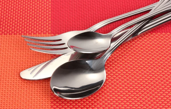 Forchetta, cucchiaio e coltello su una tovaglia rossa — Foto Stock