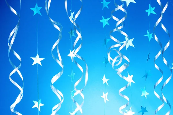 Beautiful streamers and stars on blue background — Stock Photo, Image