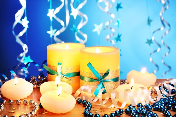 Красивые свечи, подарки и декор на деревянном столе на синем фоне — стоковое фото