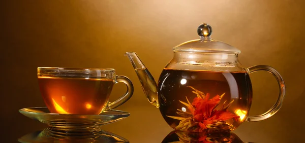 Théière en verre et tasse avec thé vert exotique sur table en bois sur fond marron — Photo