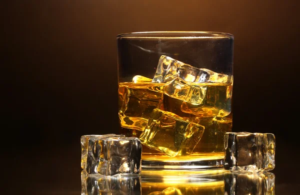 Glass of whiskey and ice on brown background — Stock Photo, Image