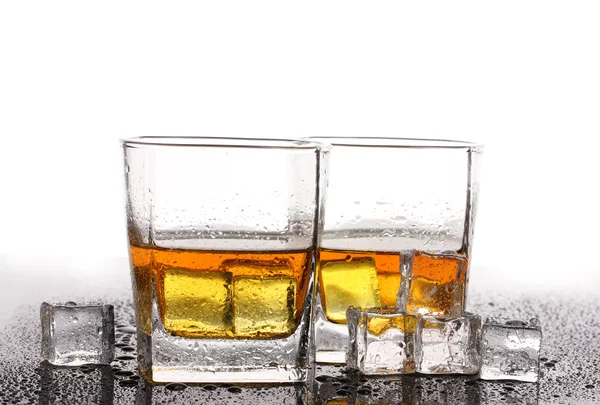 Δύο ποτήρια σκοτσέζικο ουίσκι και το πάγο στο τραπέζι που απομονώνονται σε λευκό — Φωτογραφία Αρχείου