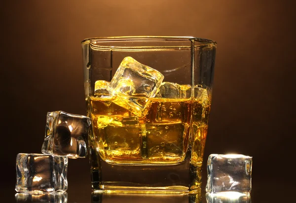 Glass of scotch whiskey and ice on brown background — Stock Photo, Image