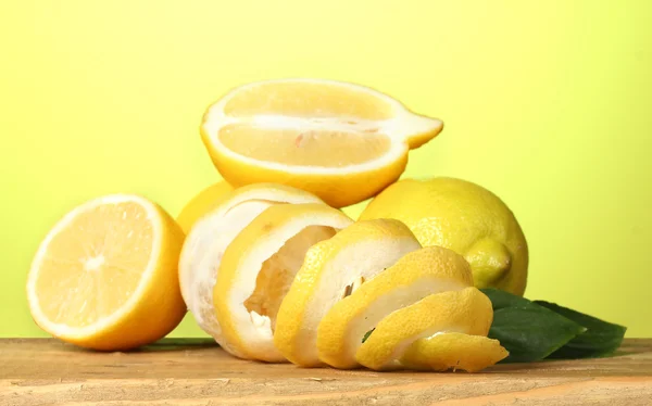 Limoni maturi con foglie su tavolo di legno su sfondo verde — Foto Stock