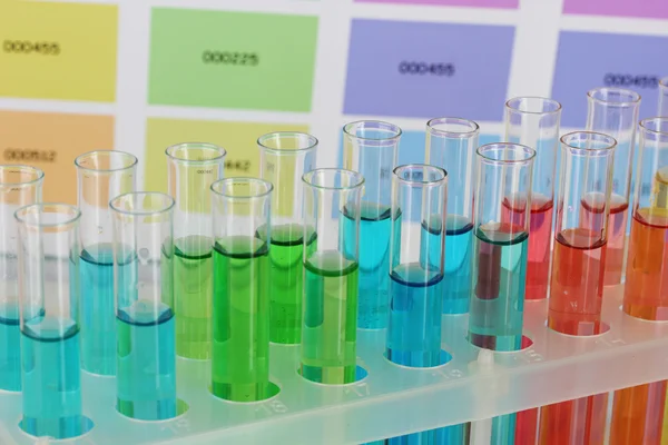 Тестові трубки з кольоровою рідиною на фоні кольорових зразків — стокове фото