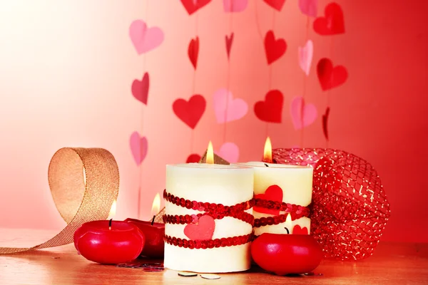 バレンタインの日赤の背景に木製のテーブルの上のキャンドル — ストック写真