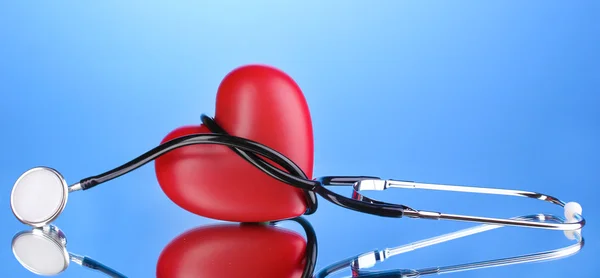 Медицинский стетоскоп и сердце на синем фоне — стоковое фото