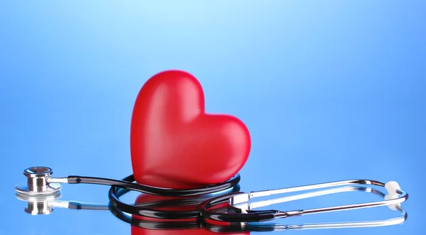 Medical stethoscope and heart on blue background — Stock Photo, Image