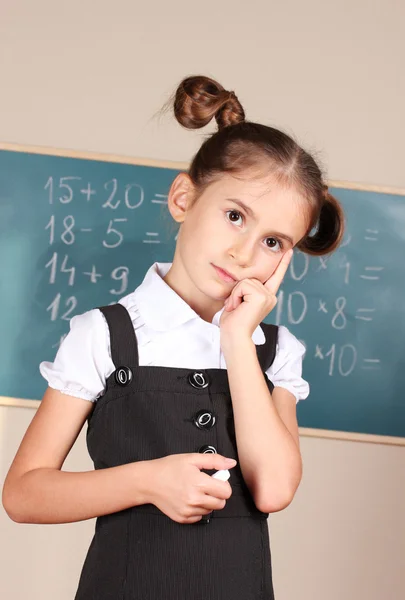 Mooi meisje permanent in de buurt van schoolbord in het klaslokaal — Stockfoto