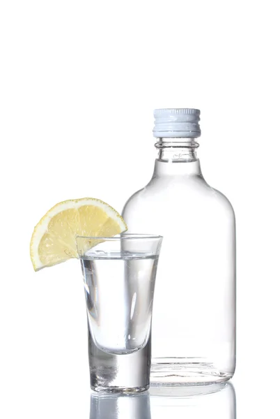 Пляшка горілки та келиха з лимоном ізольовані на білому — стокове фото