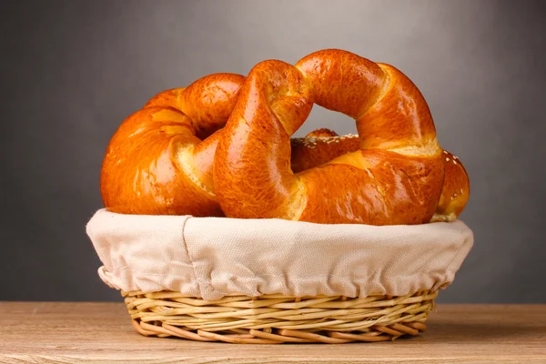 Gebakken brood in mand op houten tafel op grijze achtergrond — Stockfoto