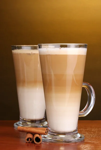 Geurige? offee latte in glazen bekers en kaneel op houten tafel op bruin b — Stockfoto