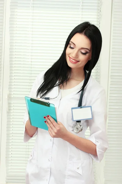 Young beautiful doctor handing folder and write — Stock Photo, Image