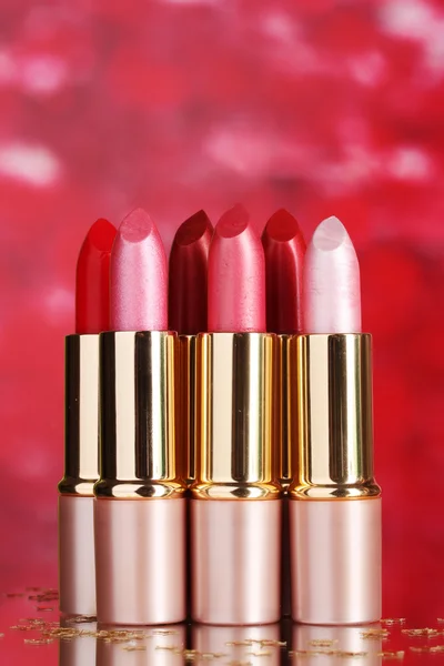 Hermosos lápices labiales sobre fondo rojo — Foto de Stock