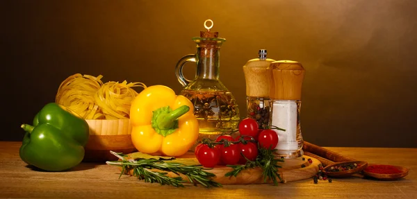 Локшина в мисці, банку з олією, спеціями та овочами на дерев'яному столі на коричневому — стокове фото