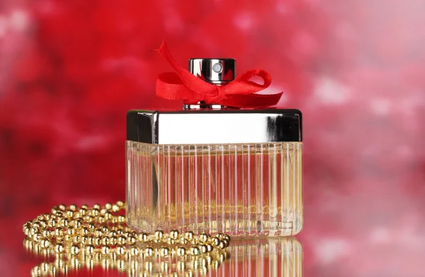Perfume bottle with red bow on red background — Zdjęcie stockowe