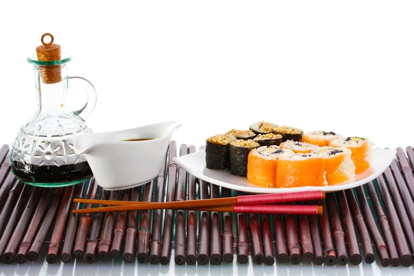 Läckra rullar serveras på vit platta med ätpinnar och sojasås på bambu m — Stockfoto