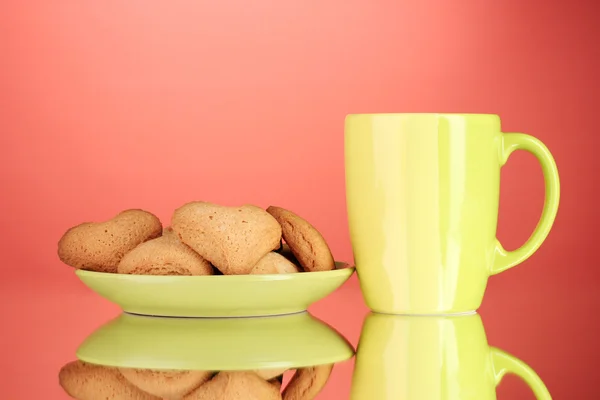 Herzförmige Kekse auf Teller und Tasse auf rotem Hintergrund — Stockfoto