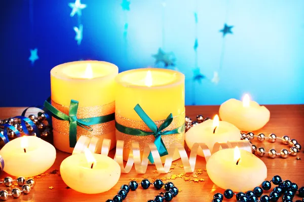 Mooie kaarsen, geschenken en decor op houten tafel op blauwe achtergrond — Stockfoto